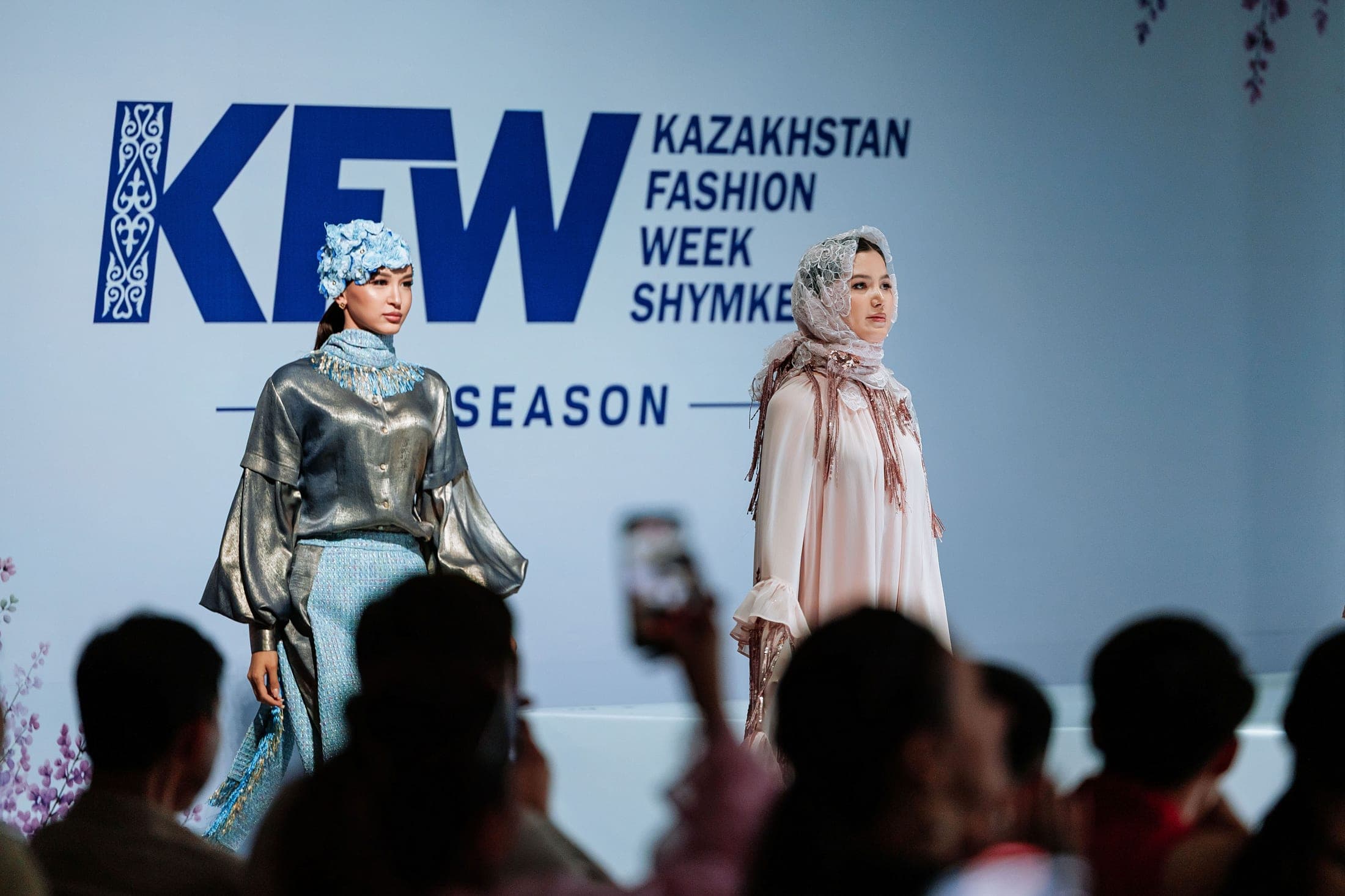 Four models on the runway in taupe ruffled, blush lace-veiled, sage-green and metallic looks